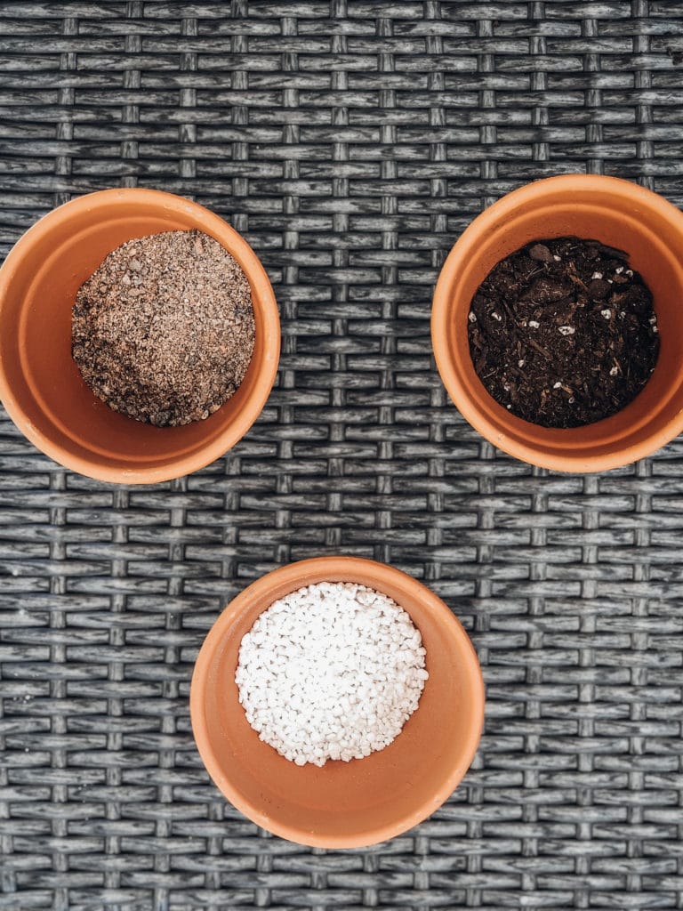 Three terra cotta pots: one pot filled with coarse sand, one with cactus mix, and one with pumice.
