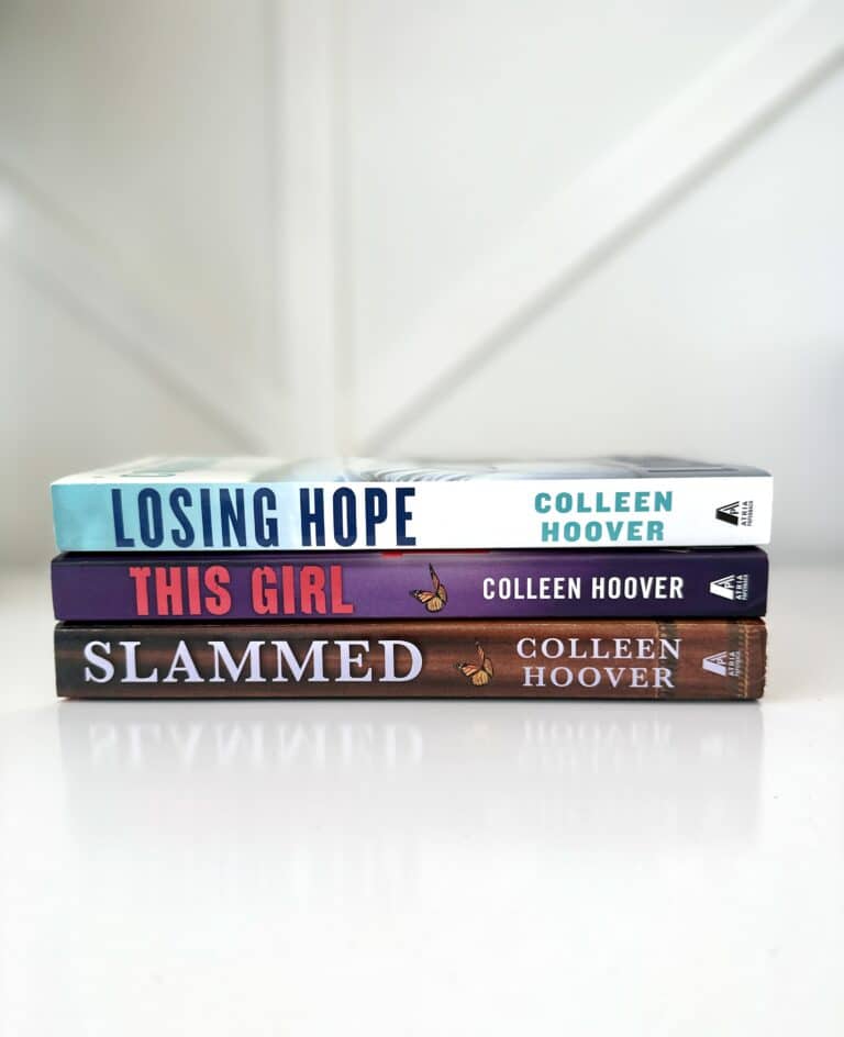 Three books laying on top of each other on white table. Titles include Slammed, this Girl, and Losing Hope, all written by author Colleen Hoover.