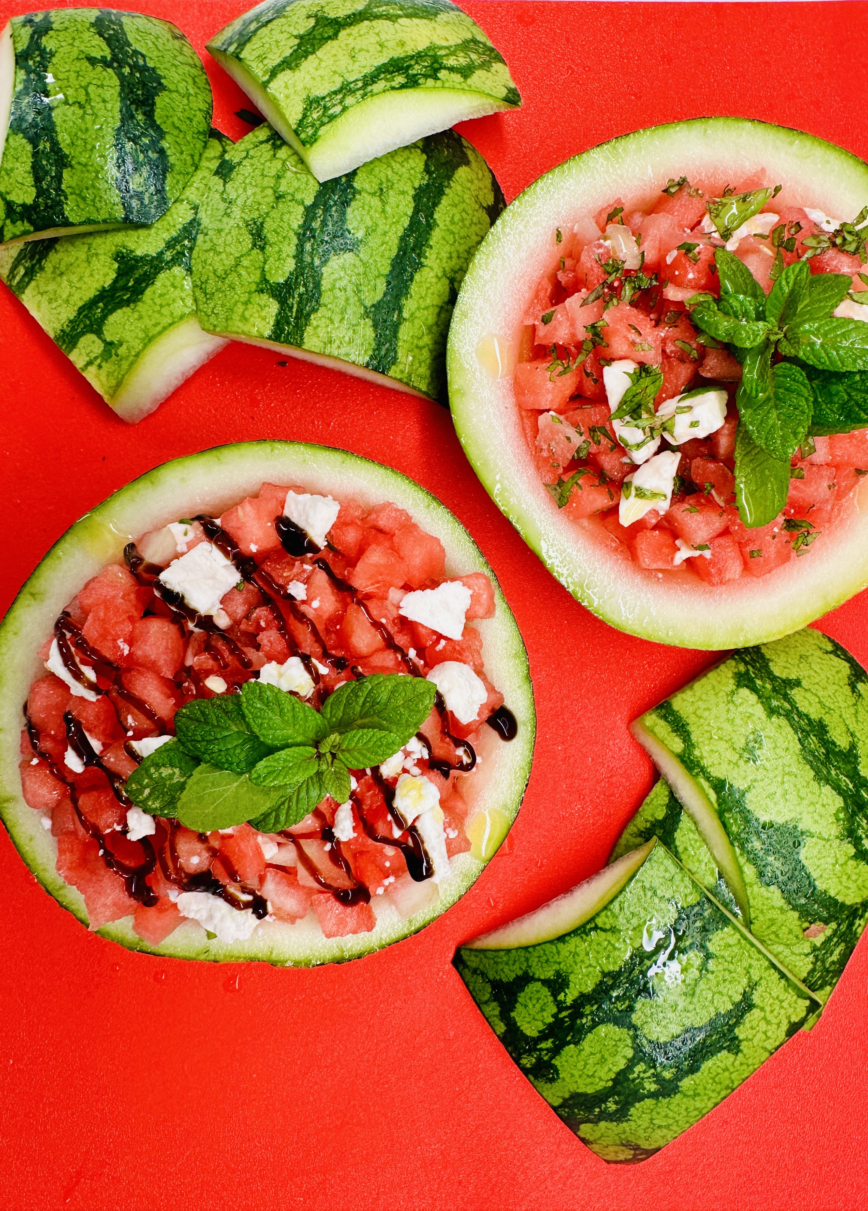 Watermelon Salad served in watermelon husks on top of red cutting board
