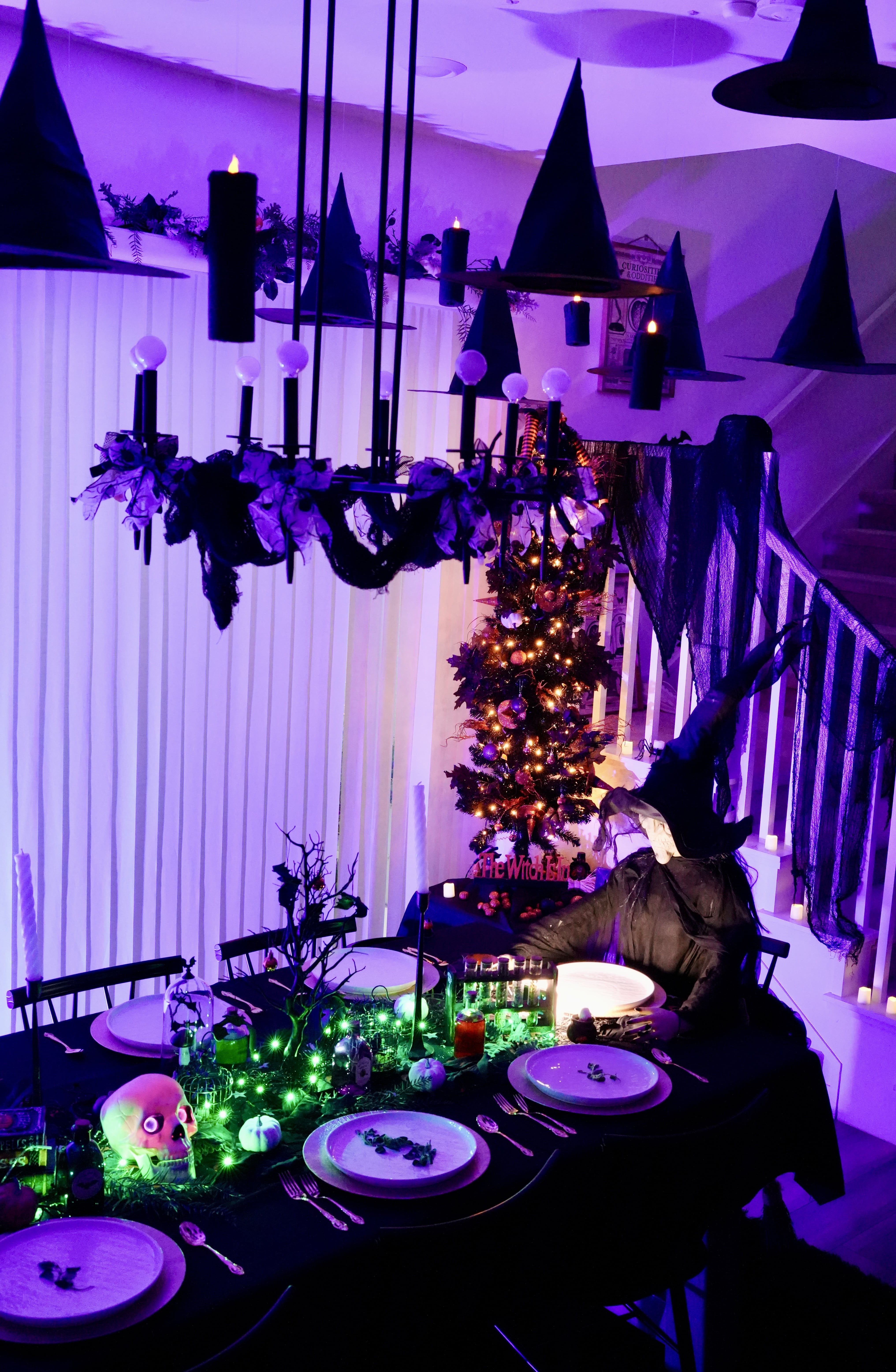 Halloween table with witch, Halloween tree, and purple lights