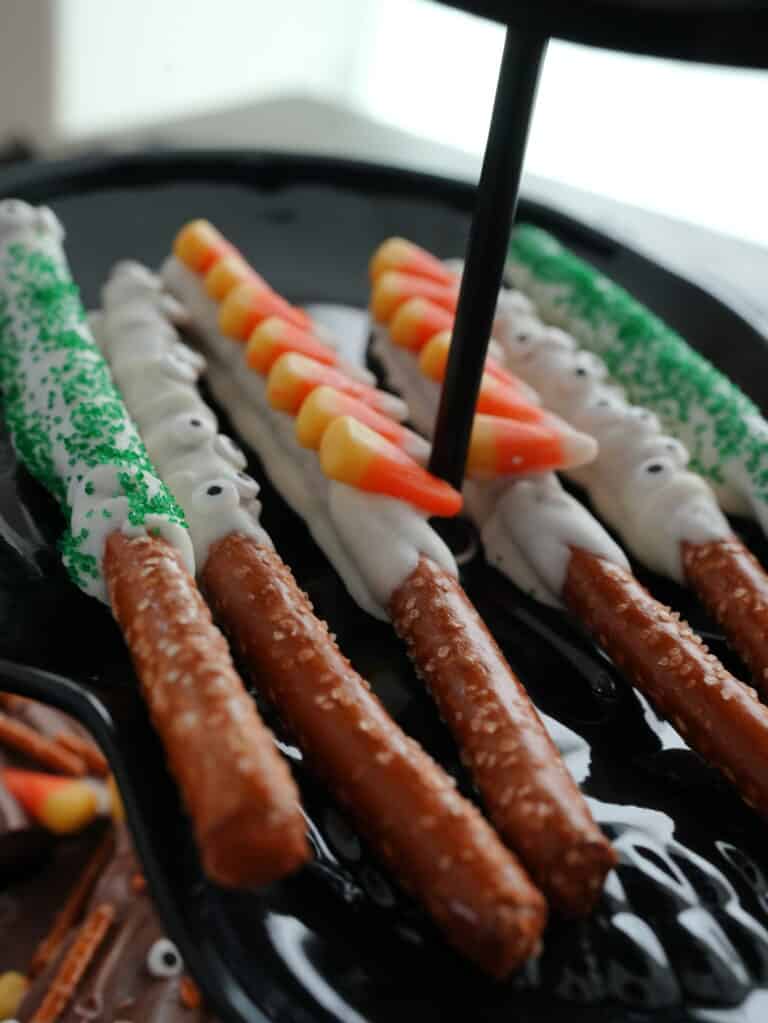 Halloween pretzel rods dipped in white chocolate and green sprinkles, candy eyes, and candy corn
