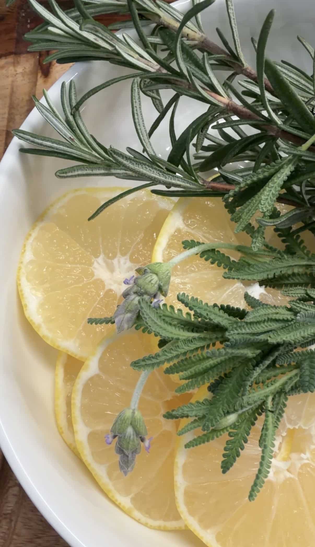 White plate filled with slices of lemon and sprigs of rosemary and lavender