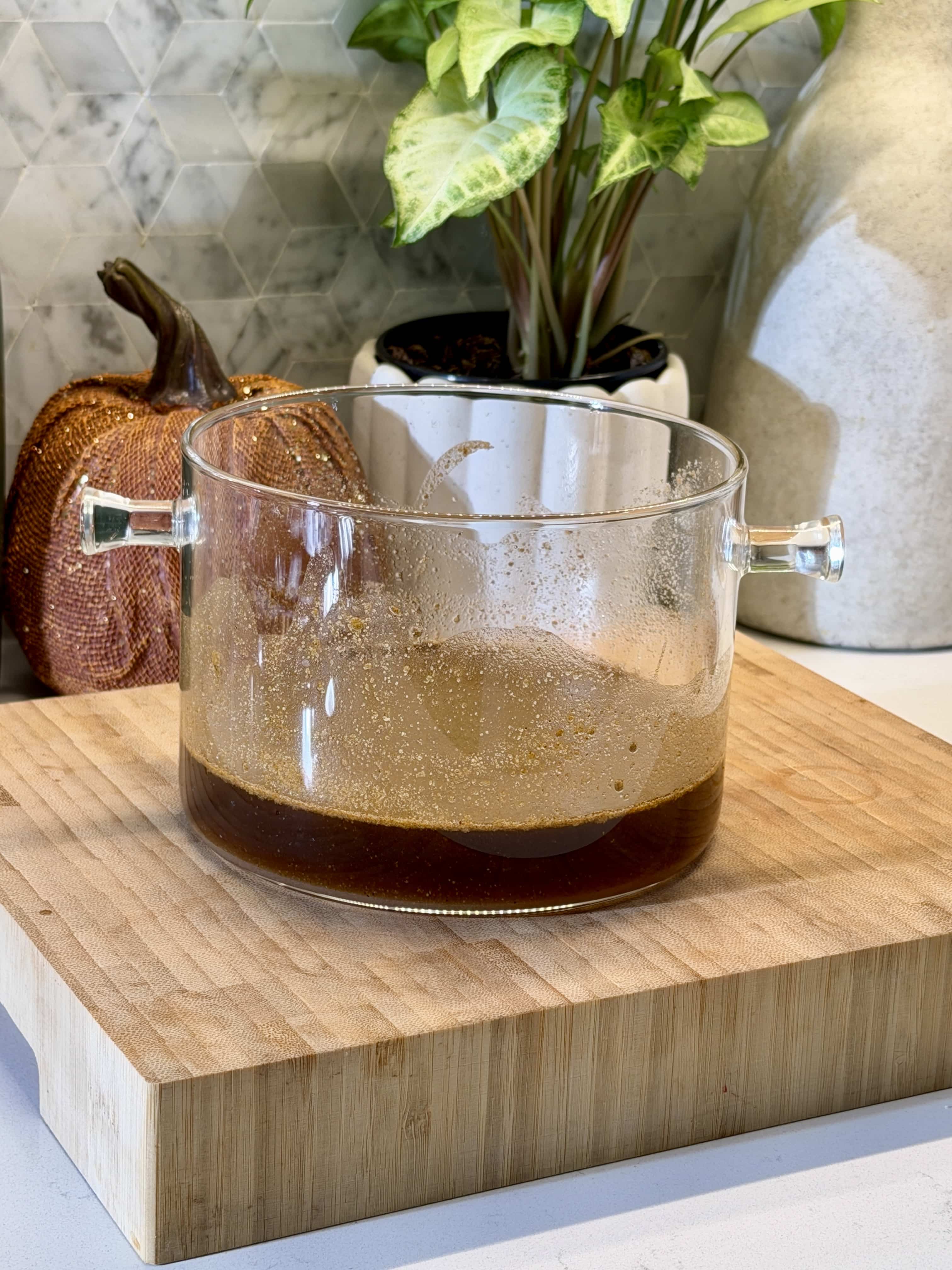 Glass simmer pot filled with ingredients for brown sugar cinnamon syrup